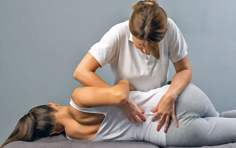 A chiropractor presses both hands into the lower back of a patient lying face down on a treatment table